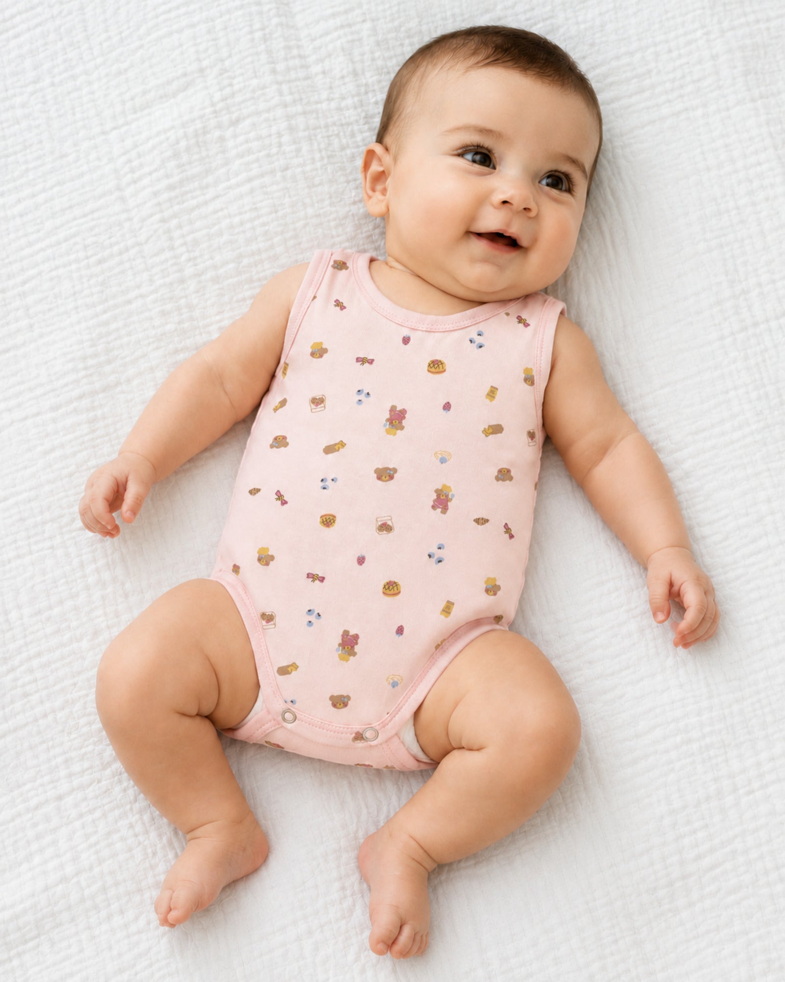 Baby wearing pale pink teddy bear and treats print sleeveless bodysuit in a bright natural use-case setting