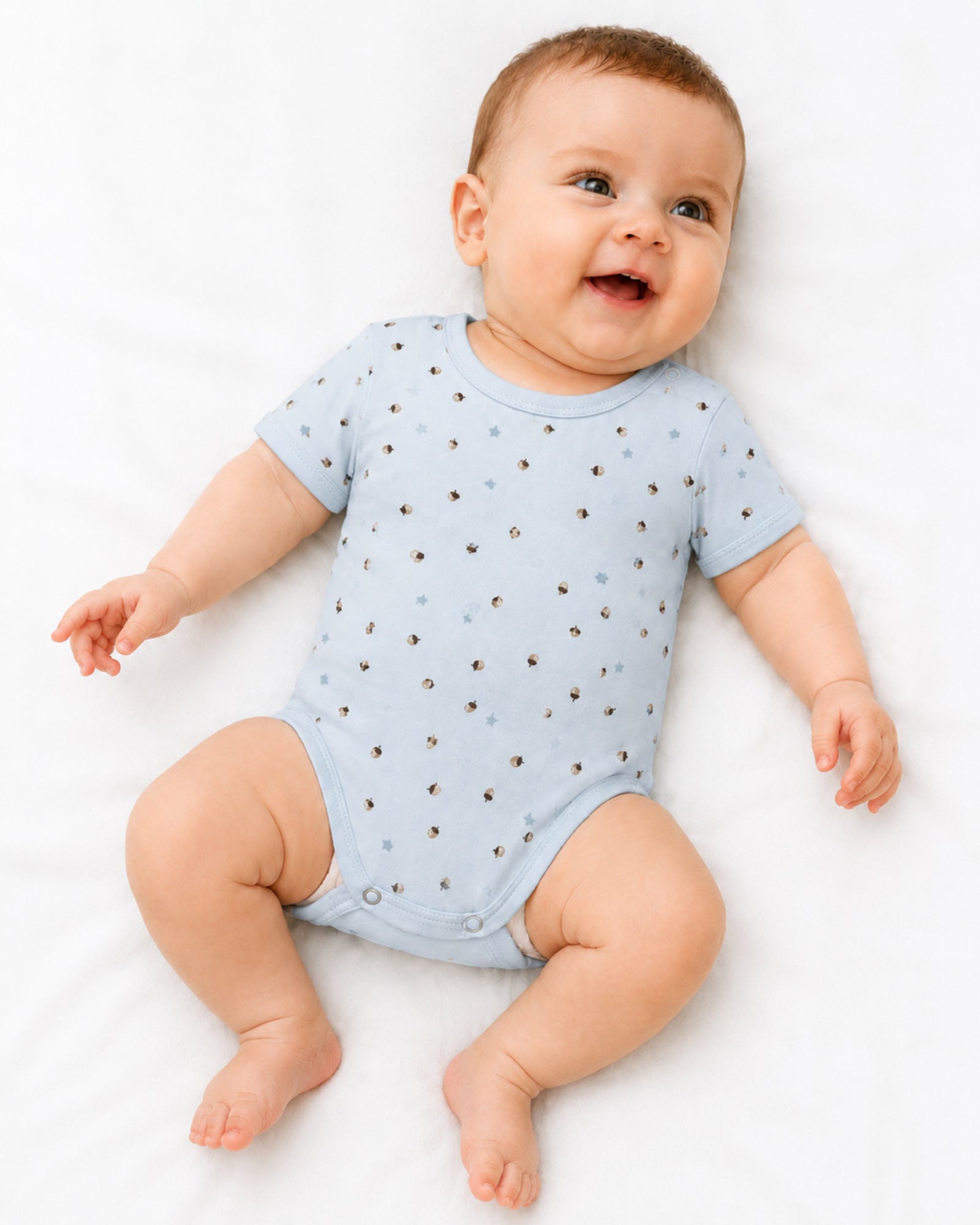 Baby wearing pale blue short-sleeve bodysuit with acorn and star print
