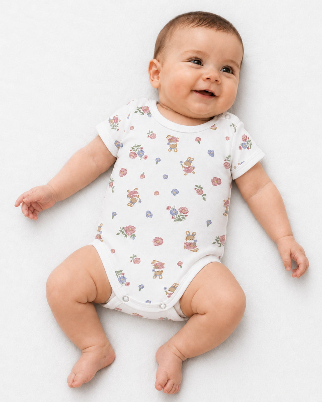 Smiling baby wearing white short-sleeve floral bunny print bodysuit on white