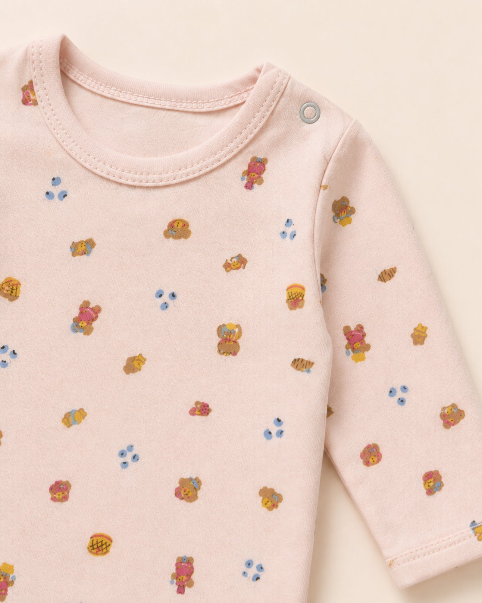 Pale pink baby set neckline, gray shoulder snap, stitching and teddy bear treats print detail