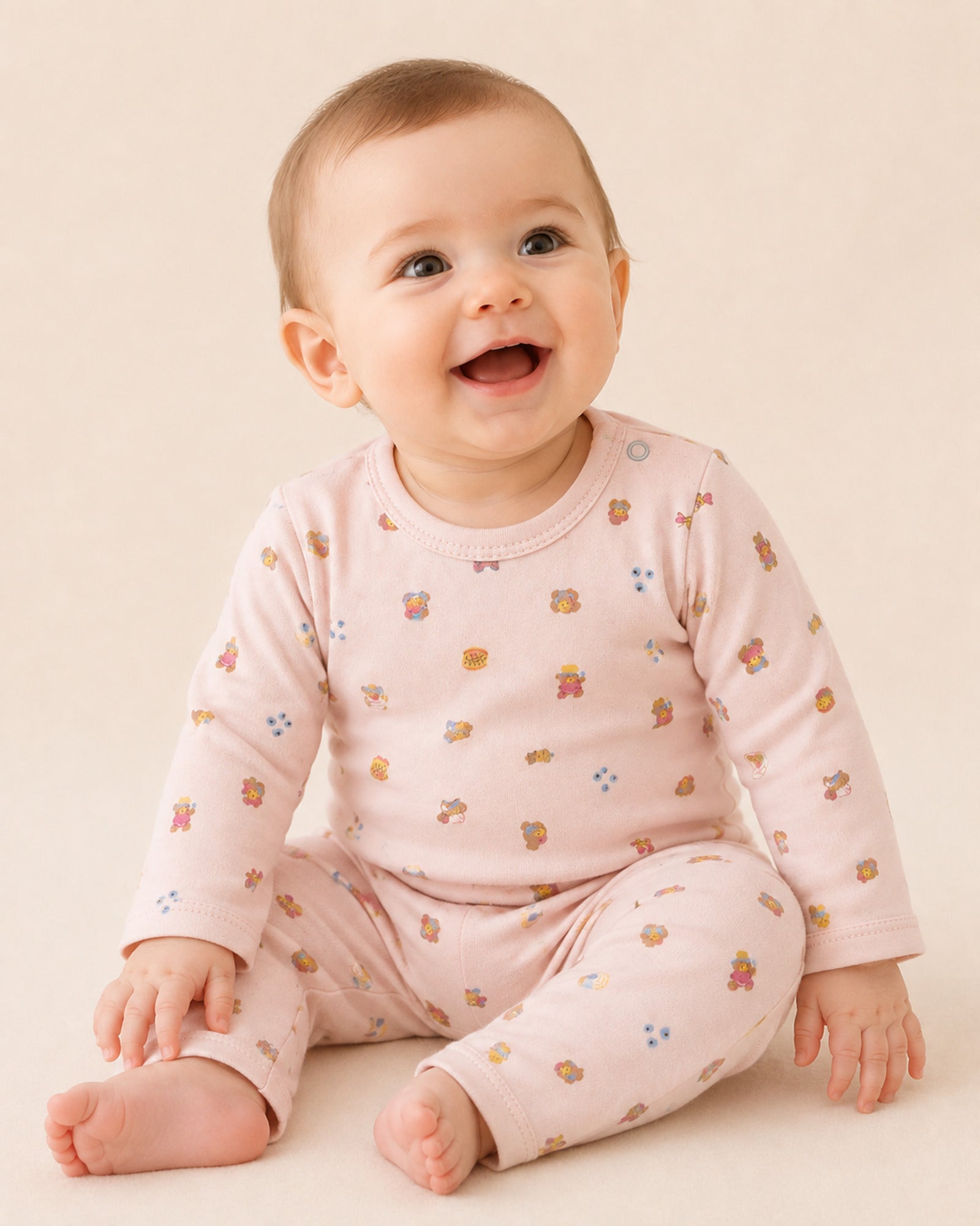 Baby wearing pale pink long-sleeve two-piece set with teddy bear treats print