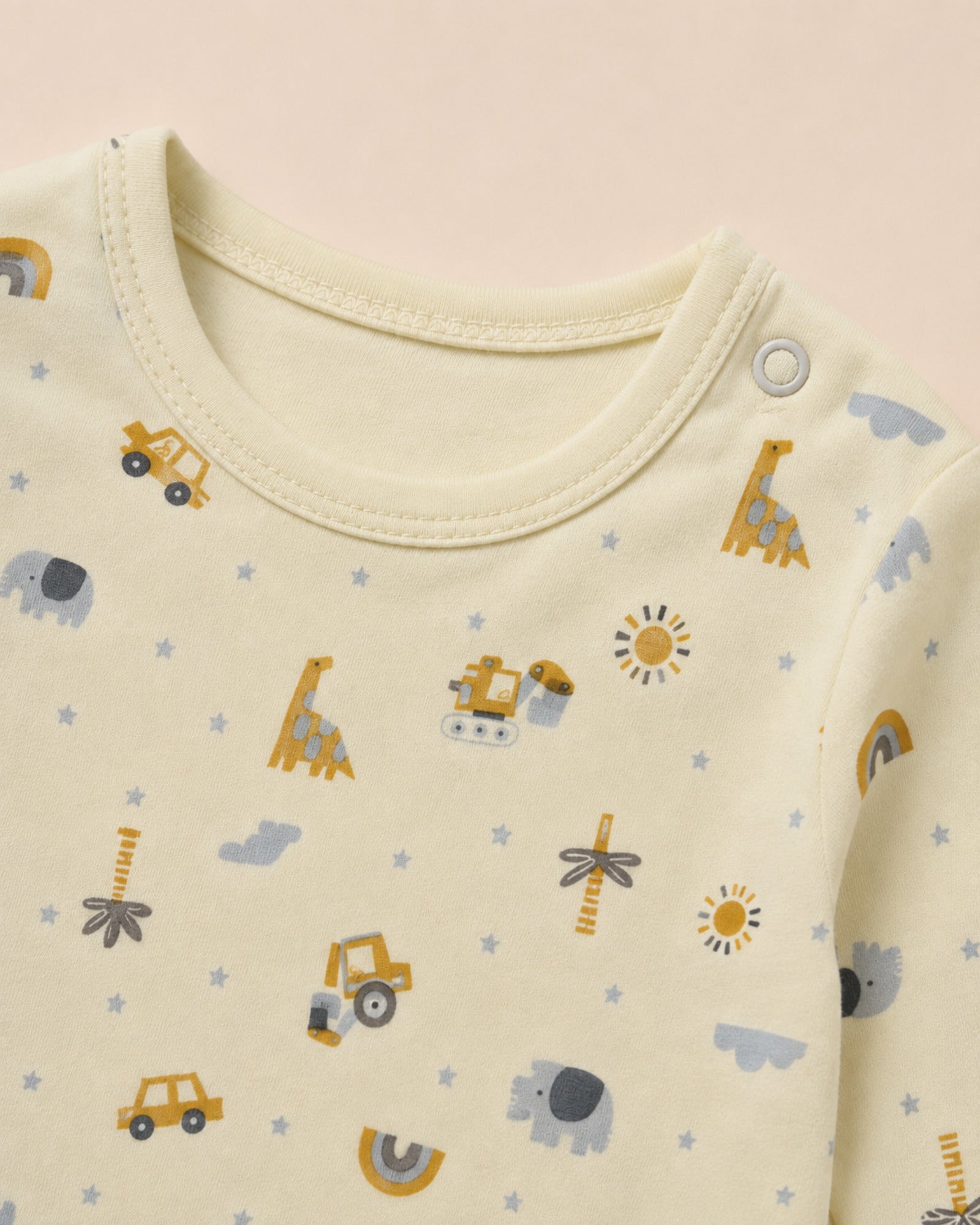 Pale buttery-yellow baby set neckline, shoulder snap, stitching and construction vehicles safari print detail