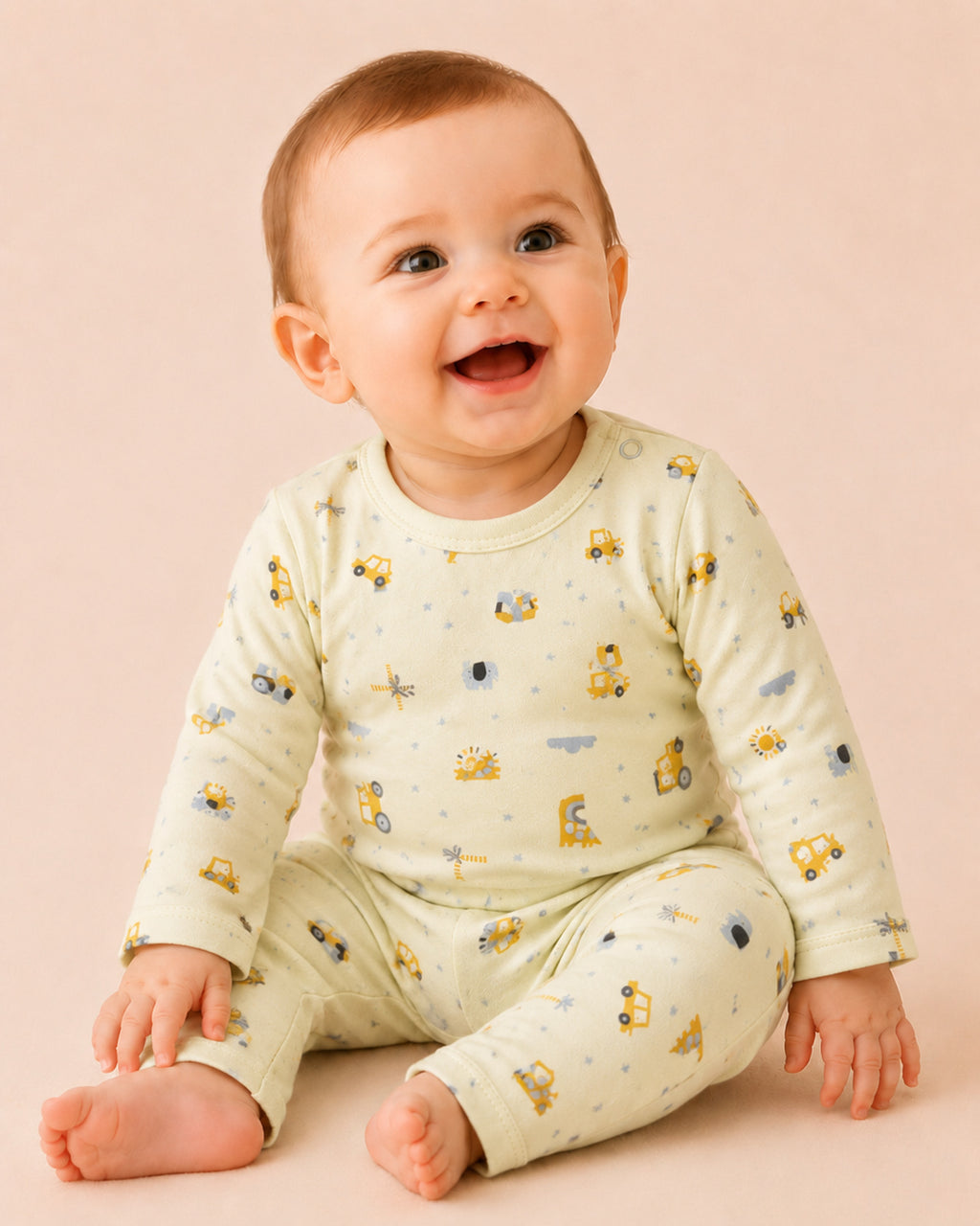 Baby wearing pale buttery-yellow long-sleeve two-piece set with construction vehicles and safari print