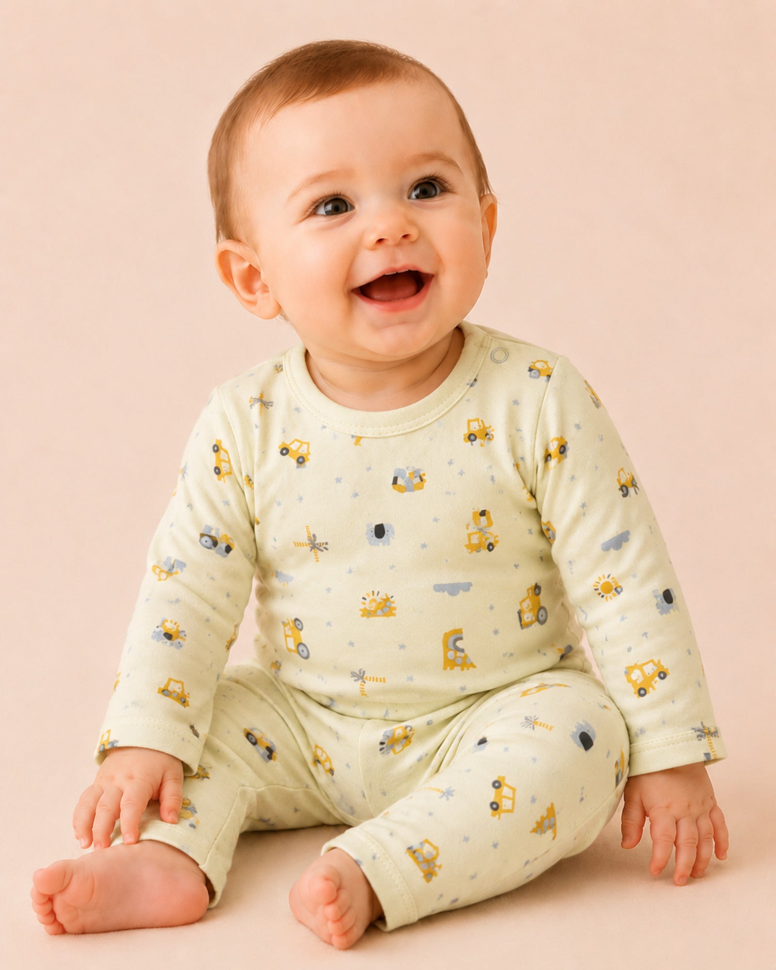 Baby wearing pale buttery-yellow long-sleeve two-piece set with construction vehicles and safari print