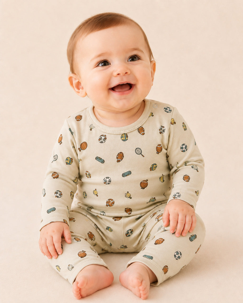 Baby wearing pale cream long-sleeve two-piece set with sports print