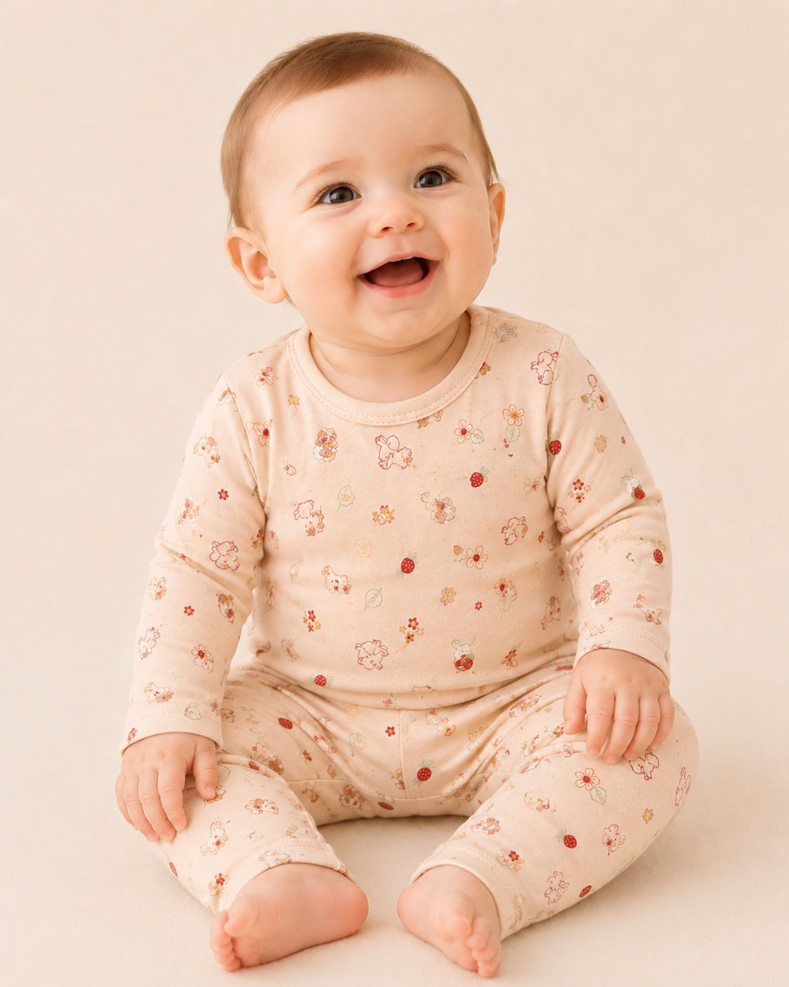 Baby wearing pale peach-pink two-piece set with bunny, flower and strawberry print