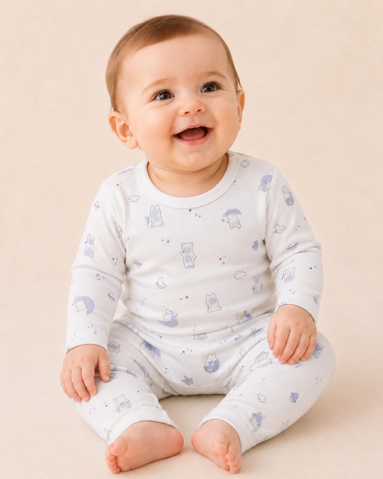 Baby wearing white two-piece set with teddy bear, moon and stars print
