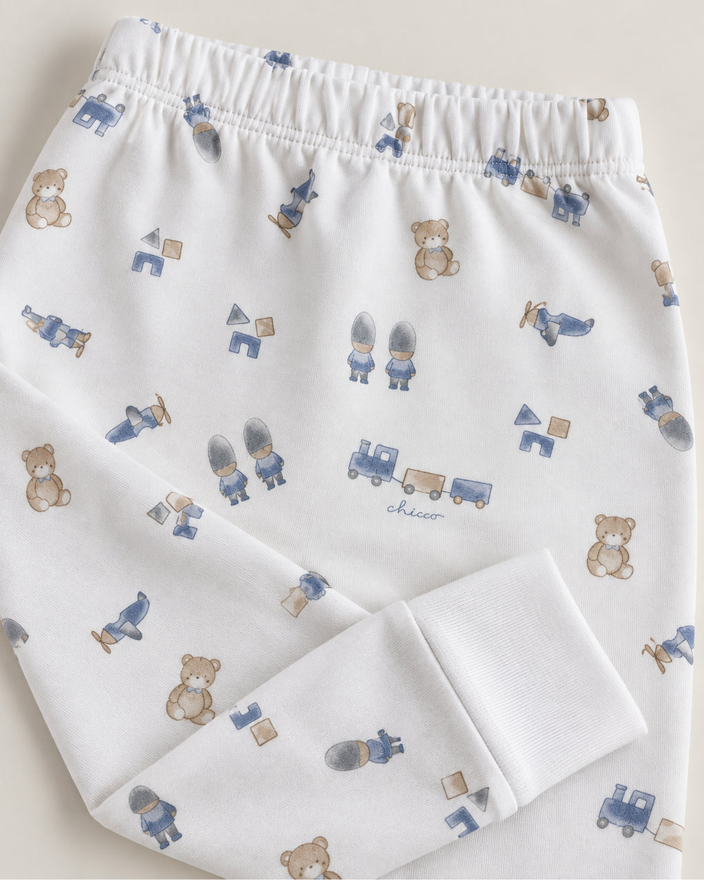 White teddy bear train and toys print trousers waistband and plain ankle cuff close-up