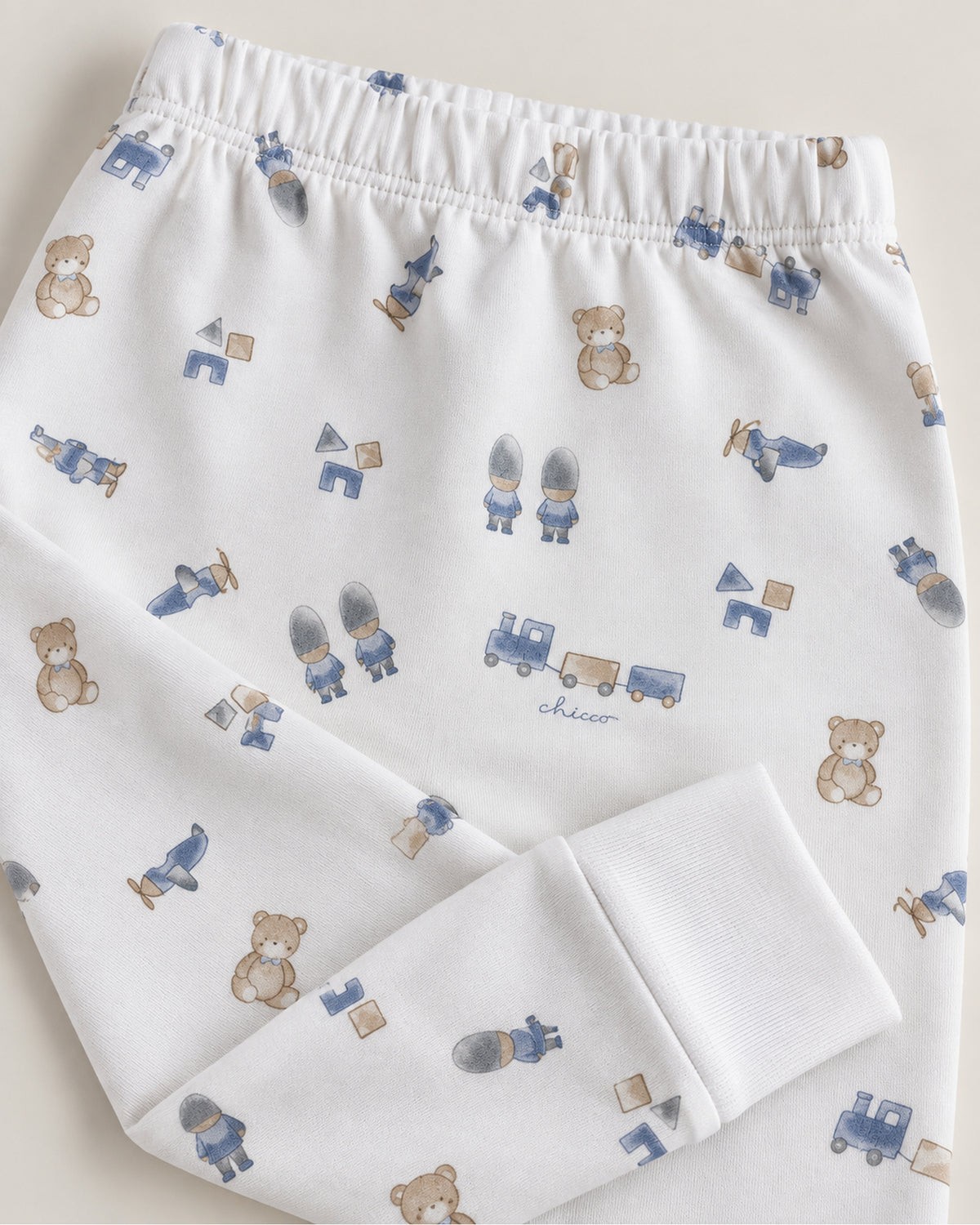 White teddy bear train and toys print trousers waistband and plain ankle cuff close-up
